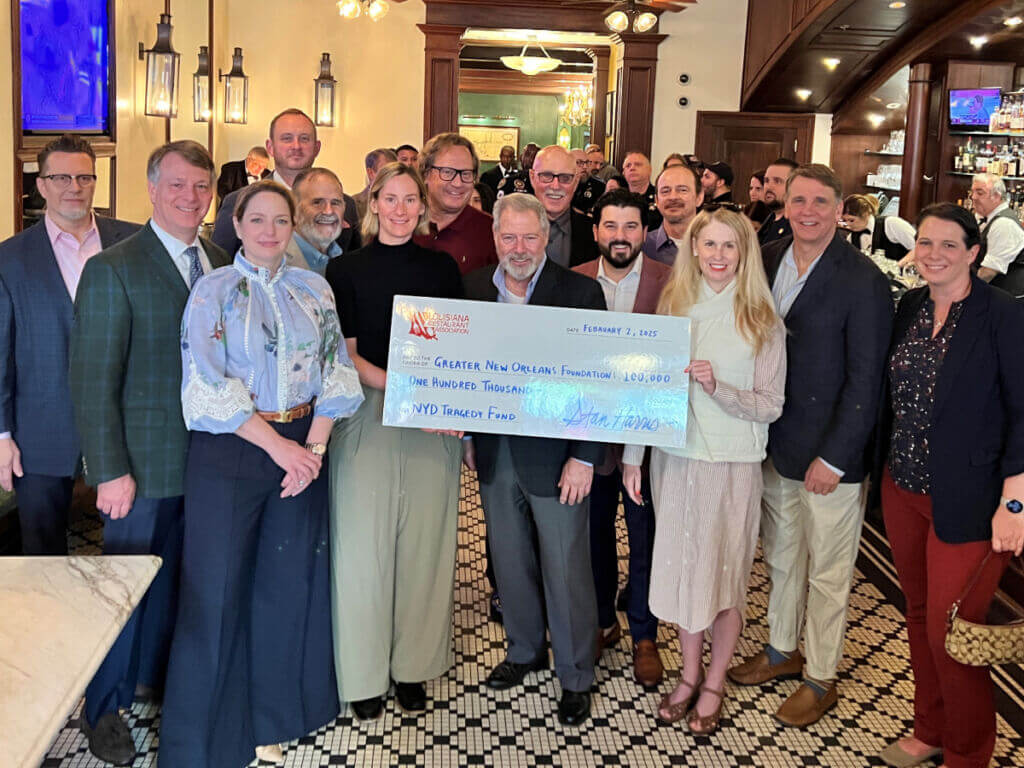 A group of people in a bar holding a large ceremonial check.