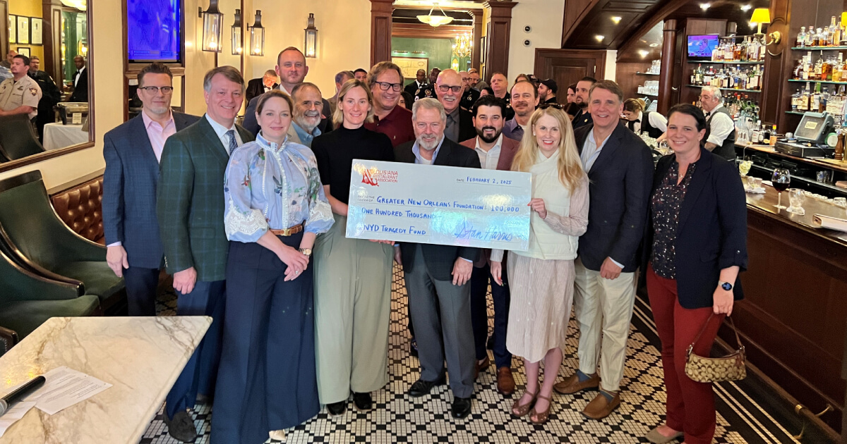 A group of people in a bar holding a large ceremonial check.