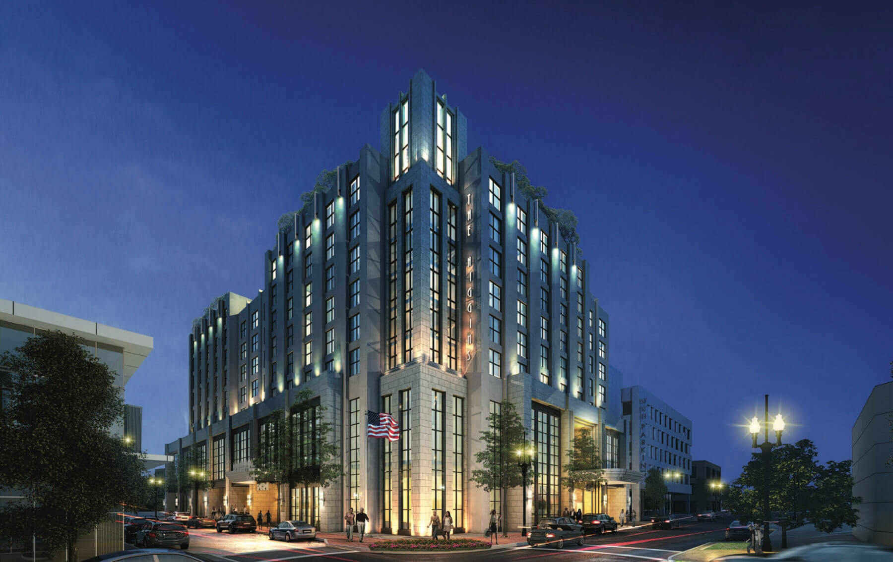 A modern, multi-story building illuminated at night, showcasing a blend of glass and stone, with trees and cars in the foreground.