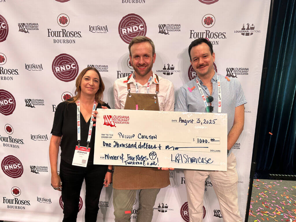 3 people posing after a competition holding an oversided check