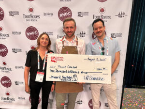 3 people posing after a competition holding an oversided check