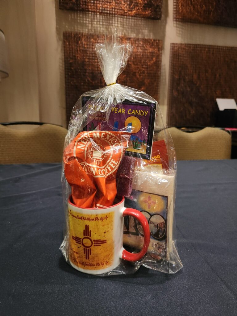 Cellophane-wrapped raffle prize containing New Mexico coffee, a mug, and candy.
