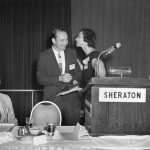 Charles Bourne (President) receiving kiss from Pauline Atherton (incoming President). Eugene Garfield on left; Mel Weinstock on right