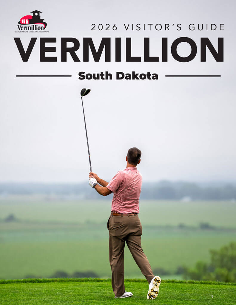 The cover of the 2026 Vermillion Visitor's Guide, showing a person swinging a golf club on the 13th hole at the Bluffs Golf Course