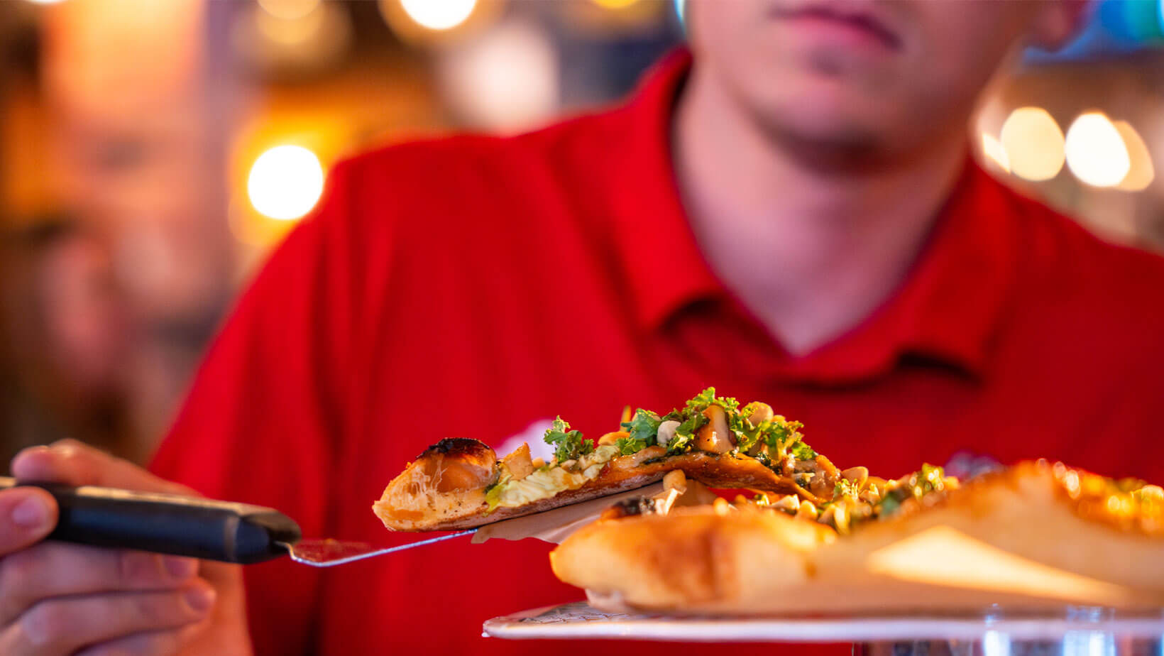 A person scoops a slice of pizza onto their plate.