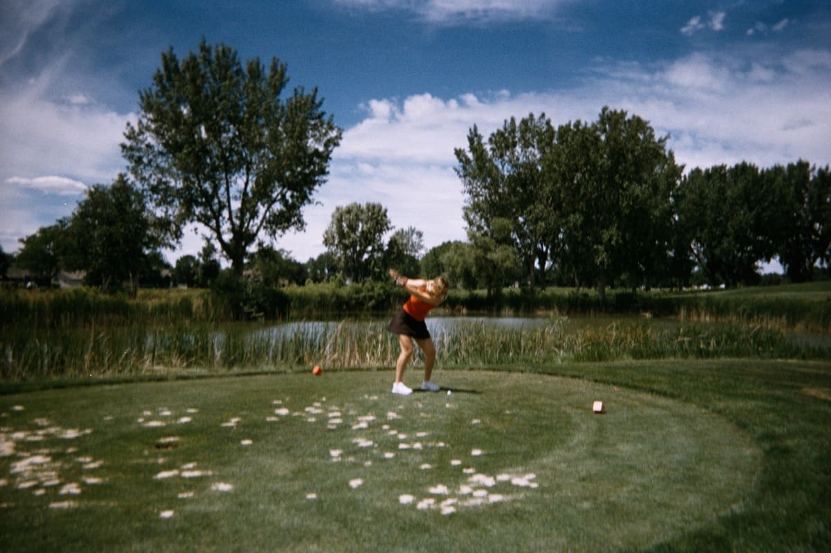 A person mid-swing, golfing.