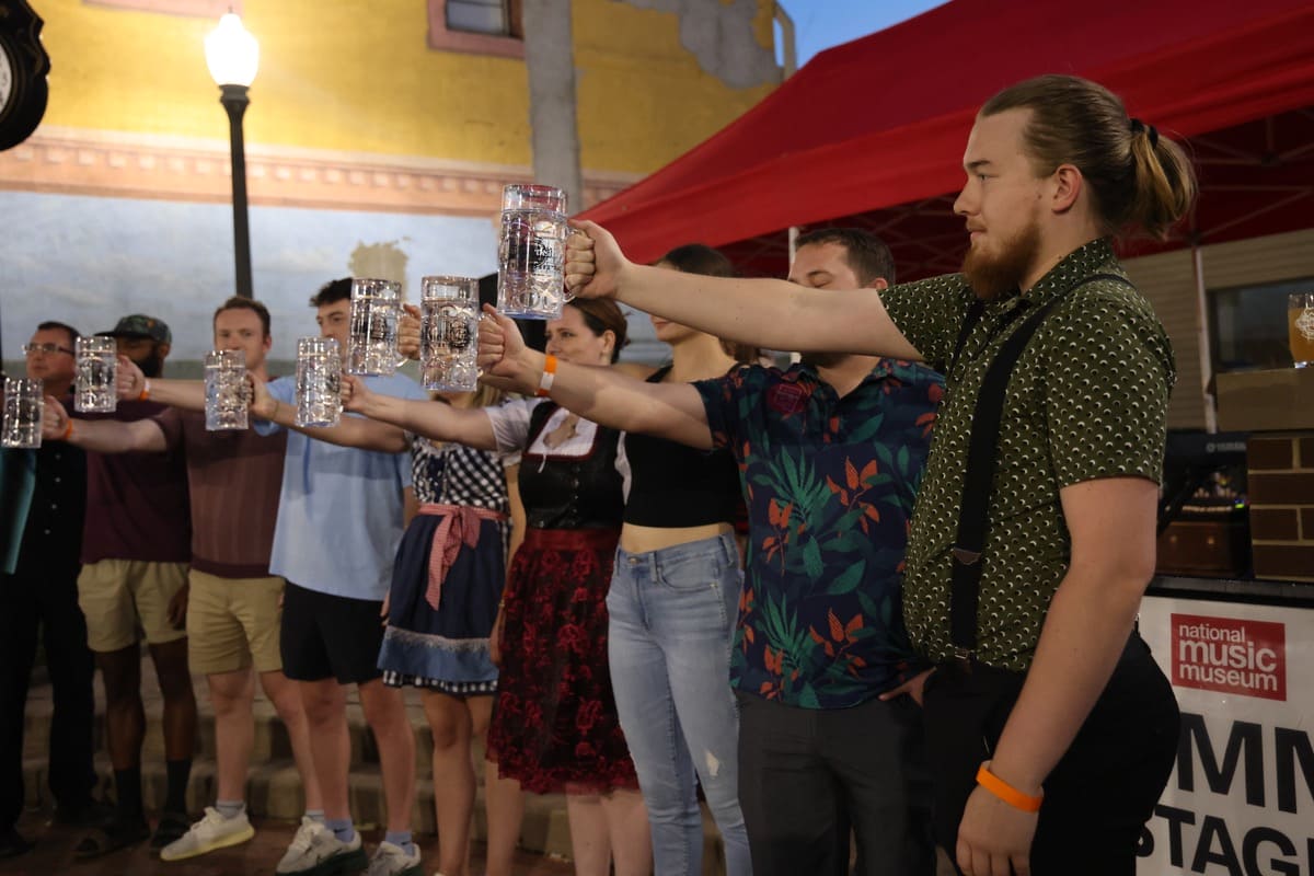 A row of people holding large steins full of water.