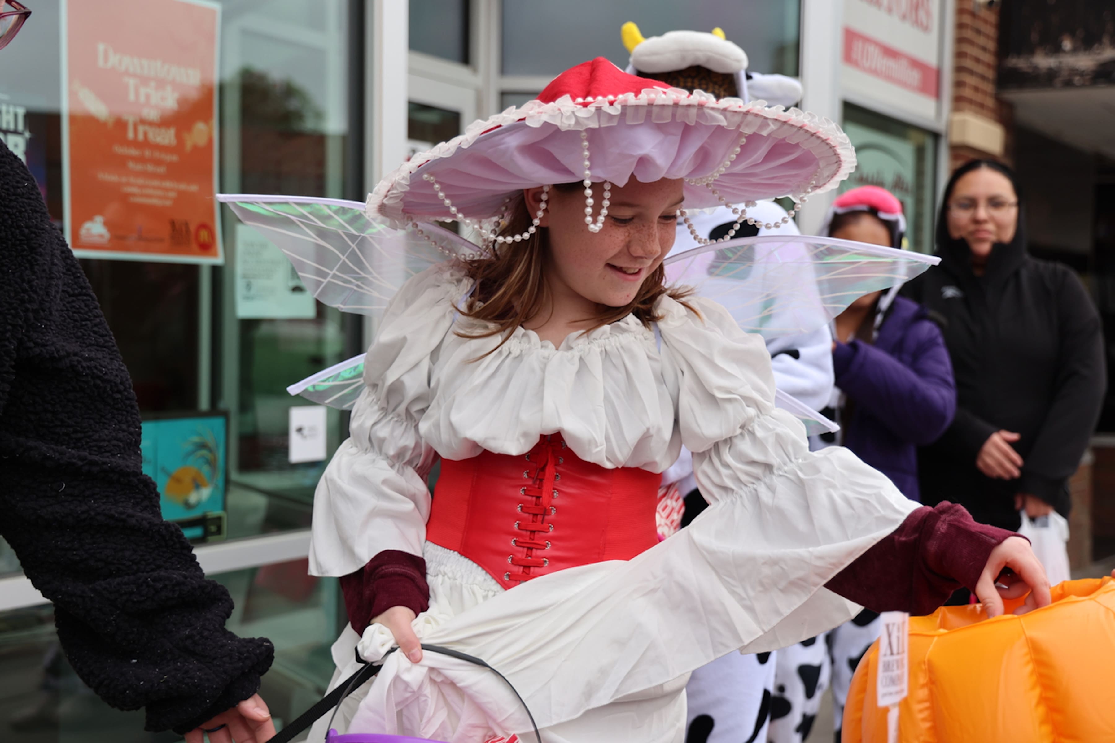 A child dressed as a fairy picks out candy from a bucket.