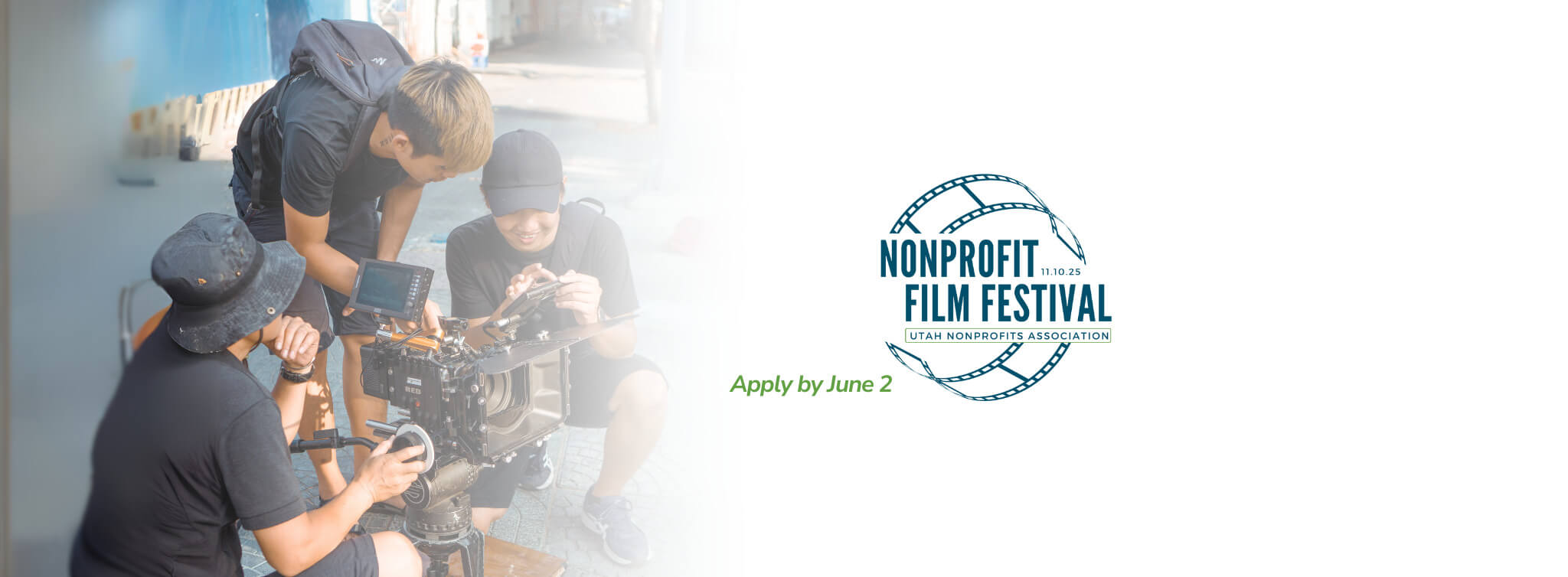 Banner with a photo of three people gathered around a film camera with the Nonprofit Film Festival logo on the right with a blurred white background fading onto the people.