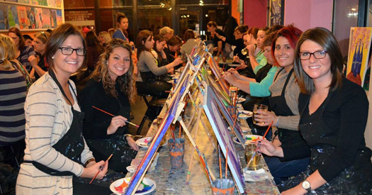 group of people painting on table easels