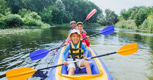 Boy with his sister and father having fun together enjoying adventurous experience kayaking on the river on a sunny day during summer vacation