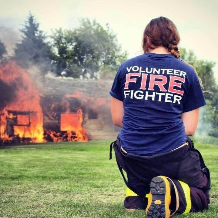 Firefighter crouching in the grass at the scene of a fire