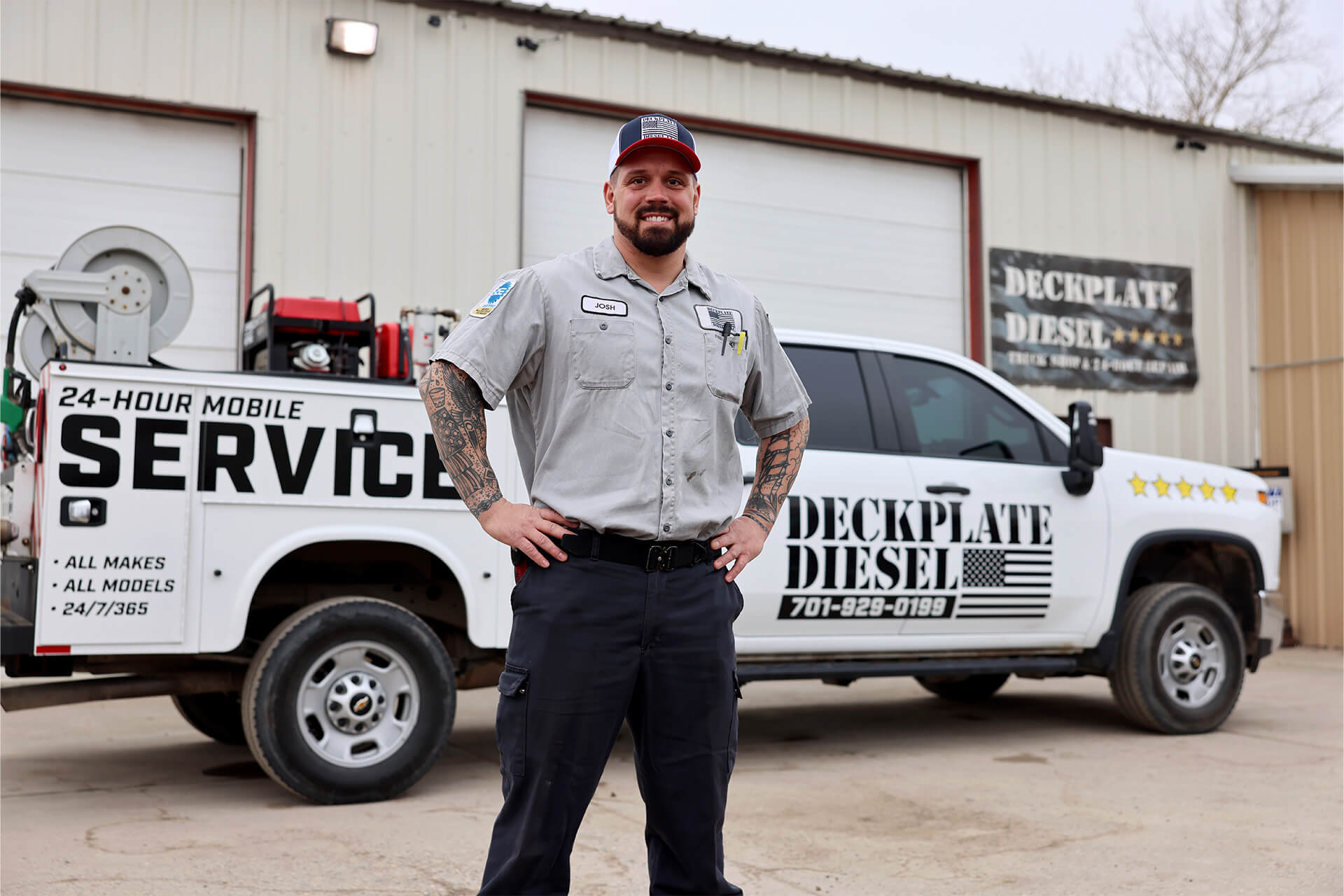 Josh Seley, Owner of Deckplate Diesel, stands in front of a white pickup that says "Deckplate Diesel," along with other promotional text on the side. This is in front of the Deckplate Diesel building in Fargo, ND.