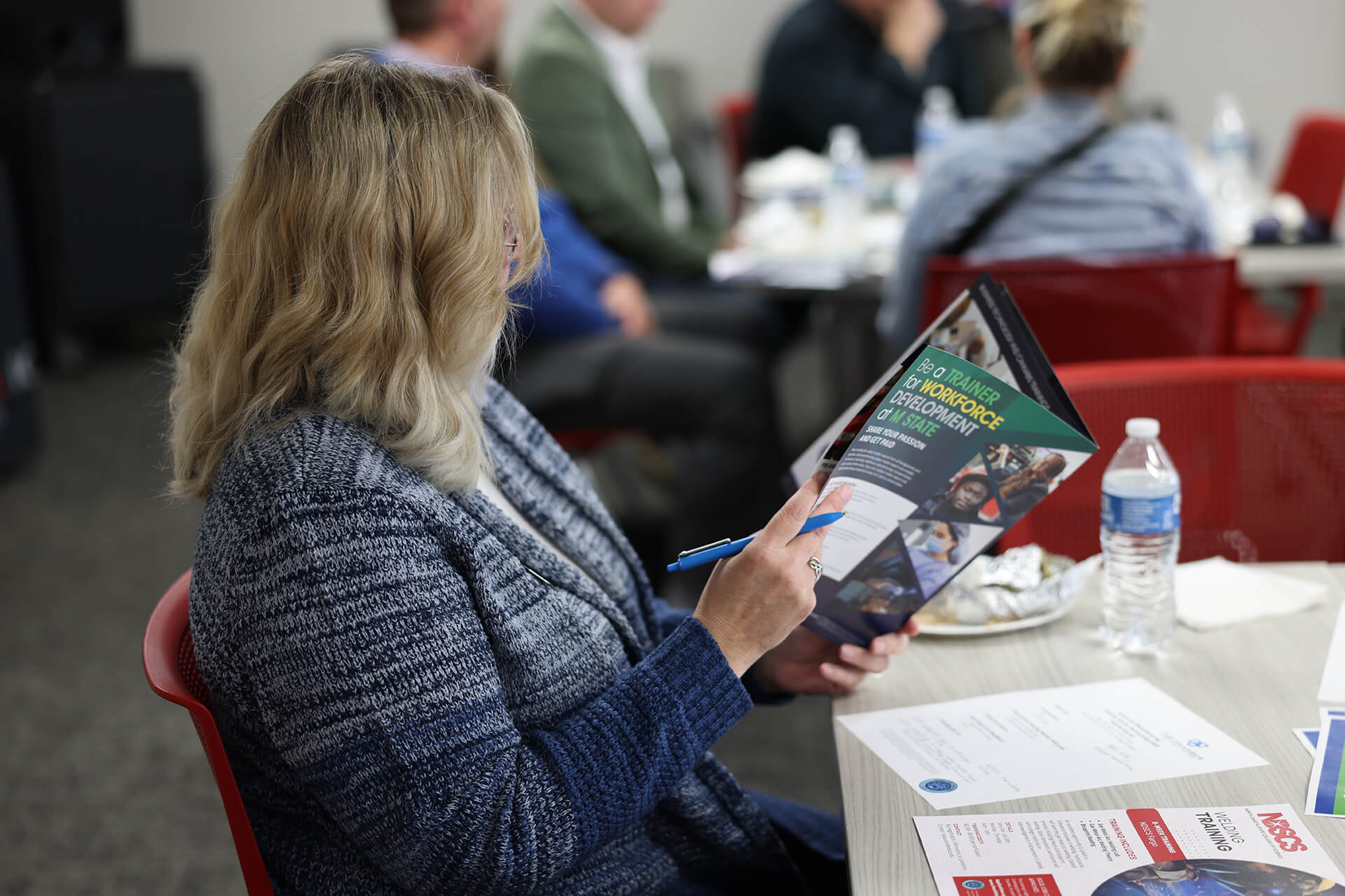 5-6-25_BlogHeader-ISP Woman reviews Minnesota State Community and Technical College booklet at the Advanced Manufacturing Industry Sector Partnership meeting in April 2025.
