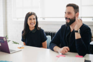 A man and women sit together at desk, discussing inclusive hiring strategies.