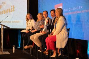 Four panelists sit on stage on the 2024 Young Professionals (YP) Summit, discussing topics like growth, imposter syndrome, and more.