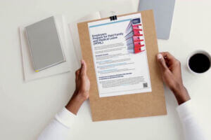 Person reviewing a PFML compliance checklist for employers about Minnesota’s Paid Family and Medical Leave program on a clipboard.