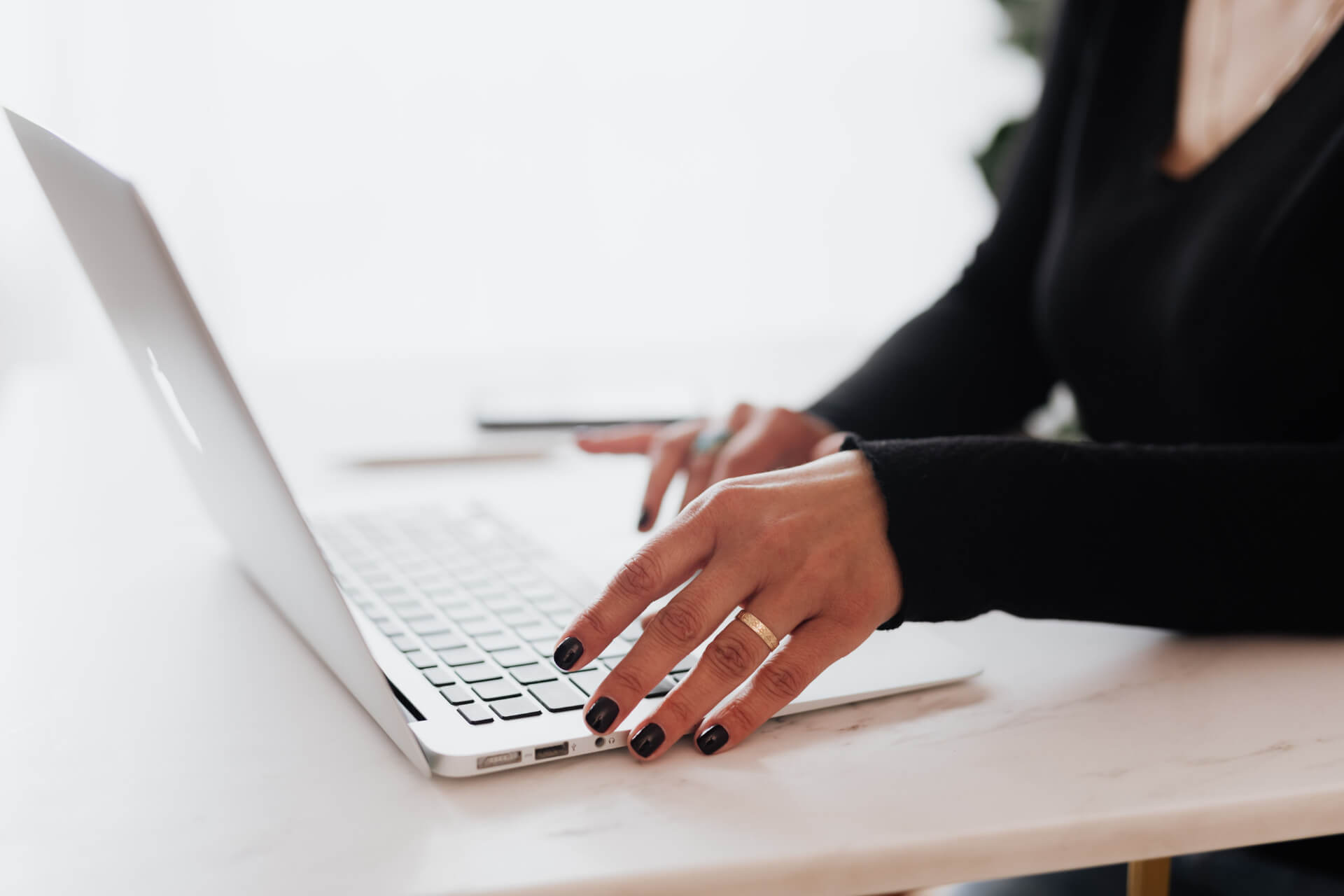 Close-up of a person typing on a laptop while managing PFML leave documents, representing employer responsibilities in PFML leave management.