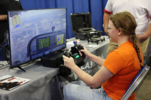 A young student sits at a flight simulator, holding pilot controls while viewing a virtual runway at the 2025 Health, Tech, and Trades Career Expo in Fargo.