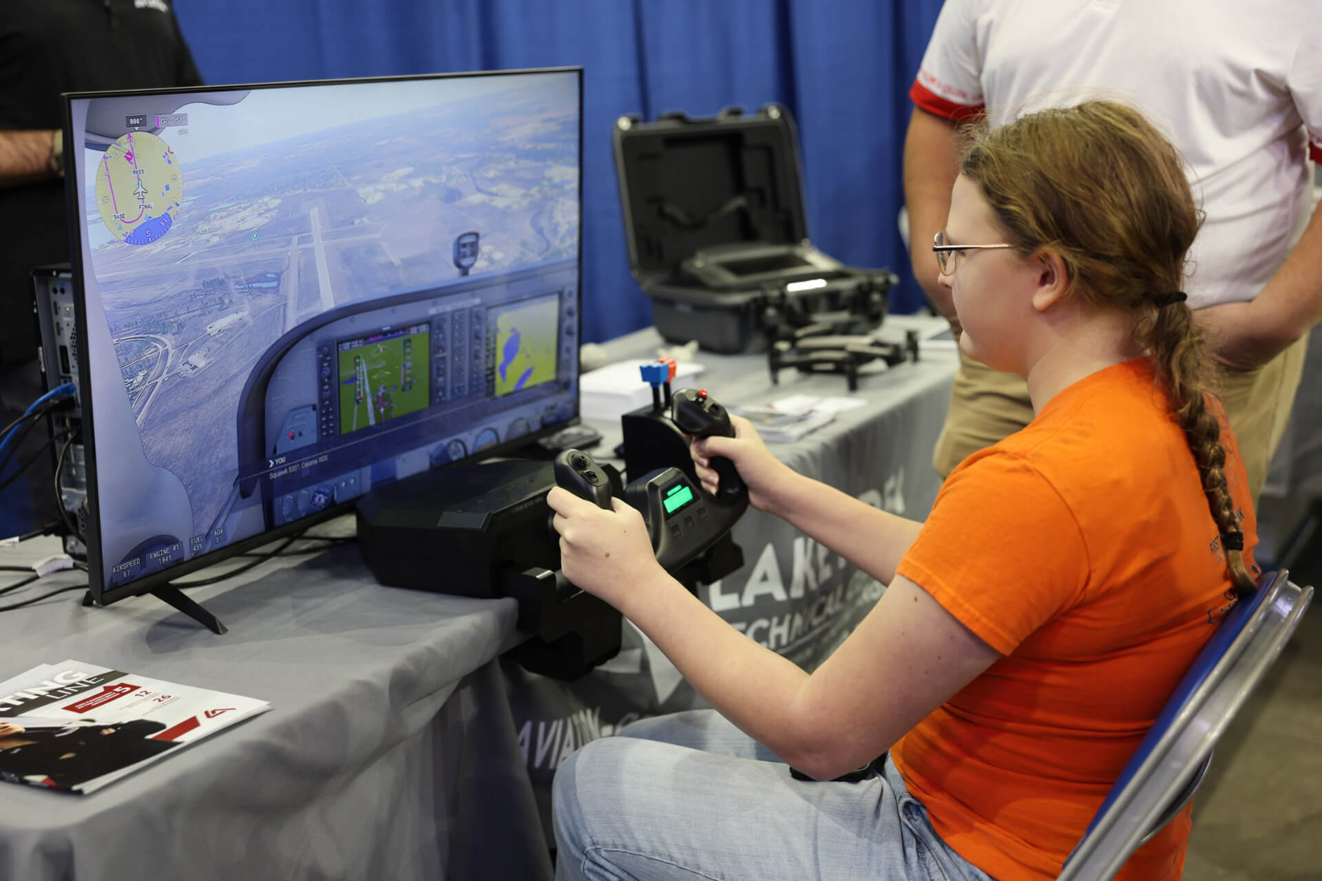 A young student sits at a flight simulator, holding pilot controls while viewing a virtual runway at the 2025 Health, Tech, and Trades Career Expo in Fargo.
