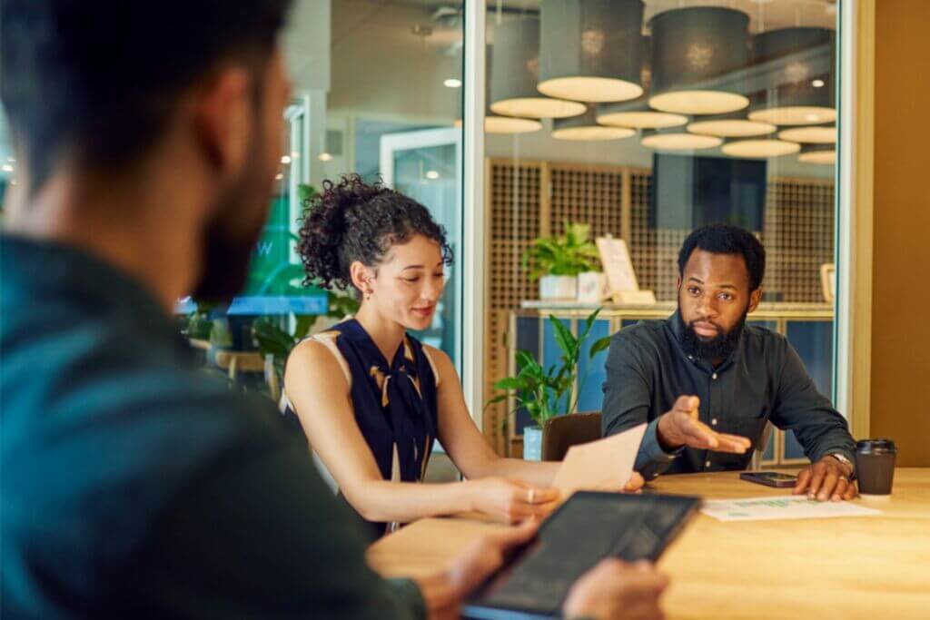 3 professionals sitting around a wooden conference table