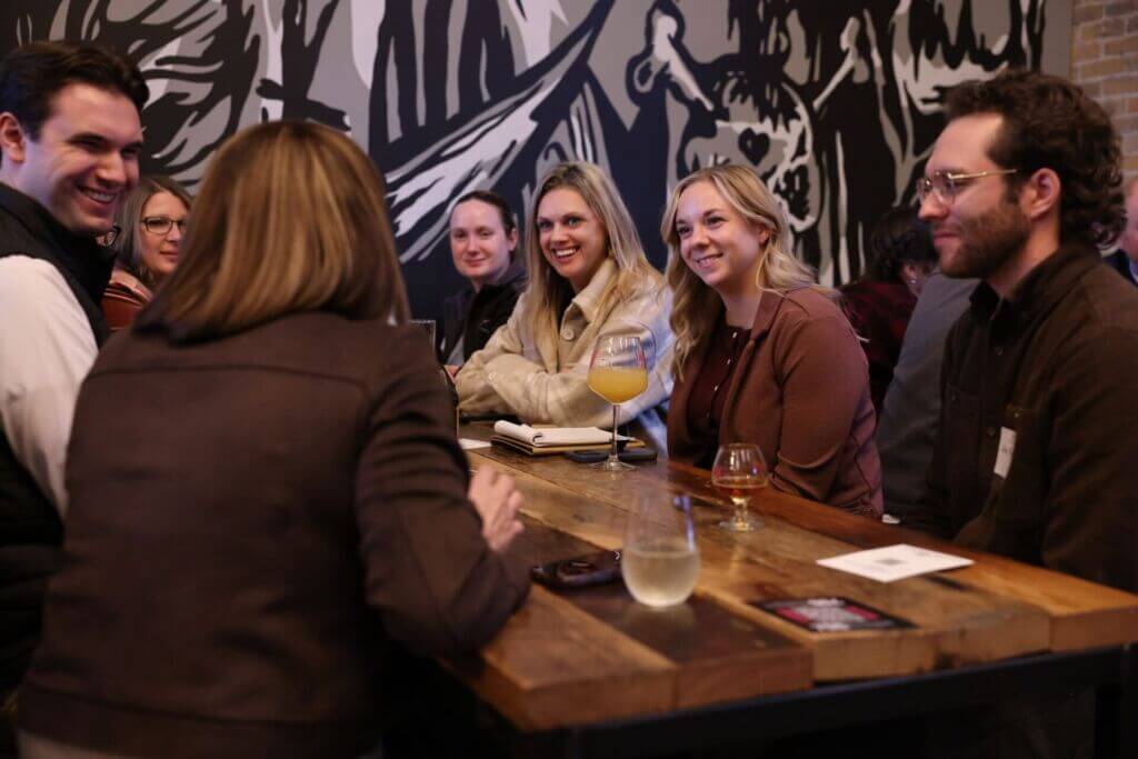 Attendees gathered around a table in discussion during the Civics on Tap civic engagement event hosted by the FMWF Chamber at Drekker Brewing Company in Fargo.