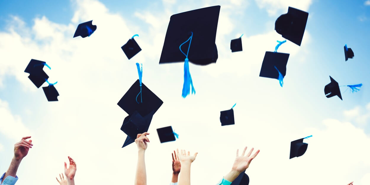 graduates' hands tossing caps in the air