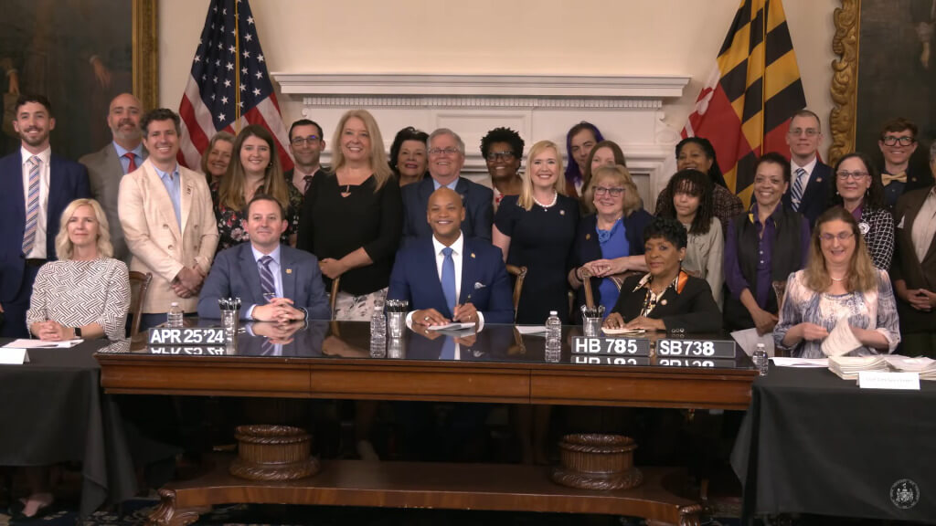 Governor Moore, surrounded by Maryland delegates and library supporters, signs the Freedom to Read Act