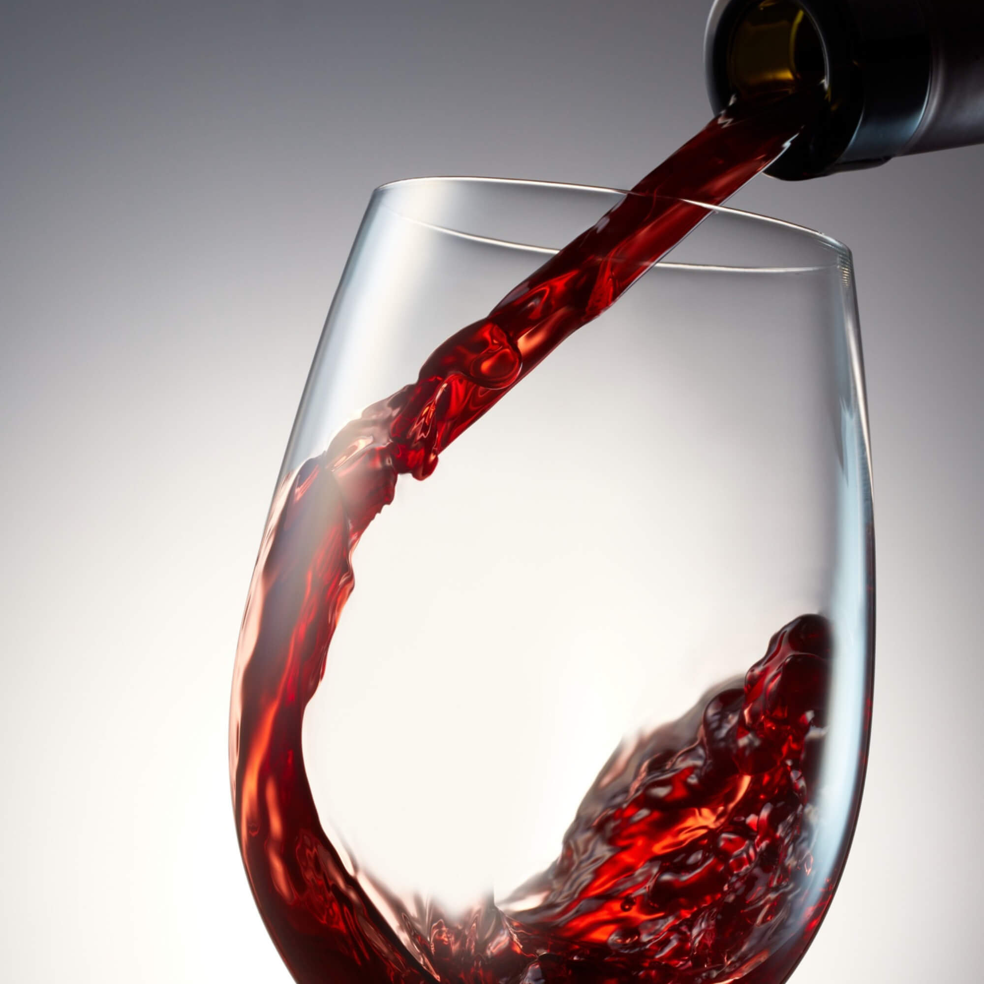 close up image of red wine being poured into glass