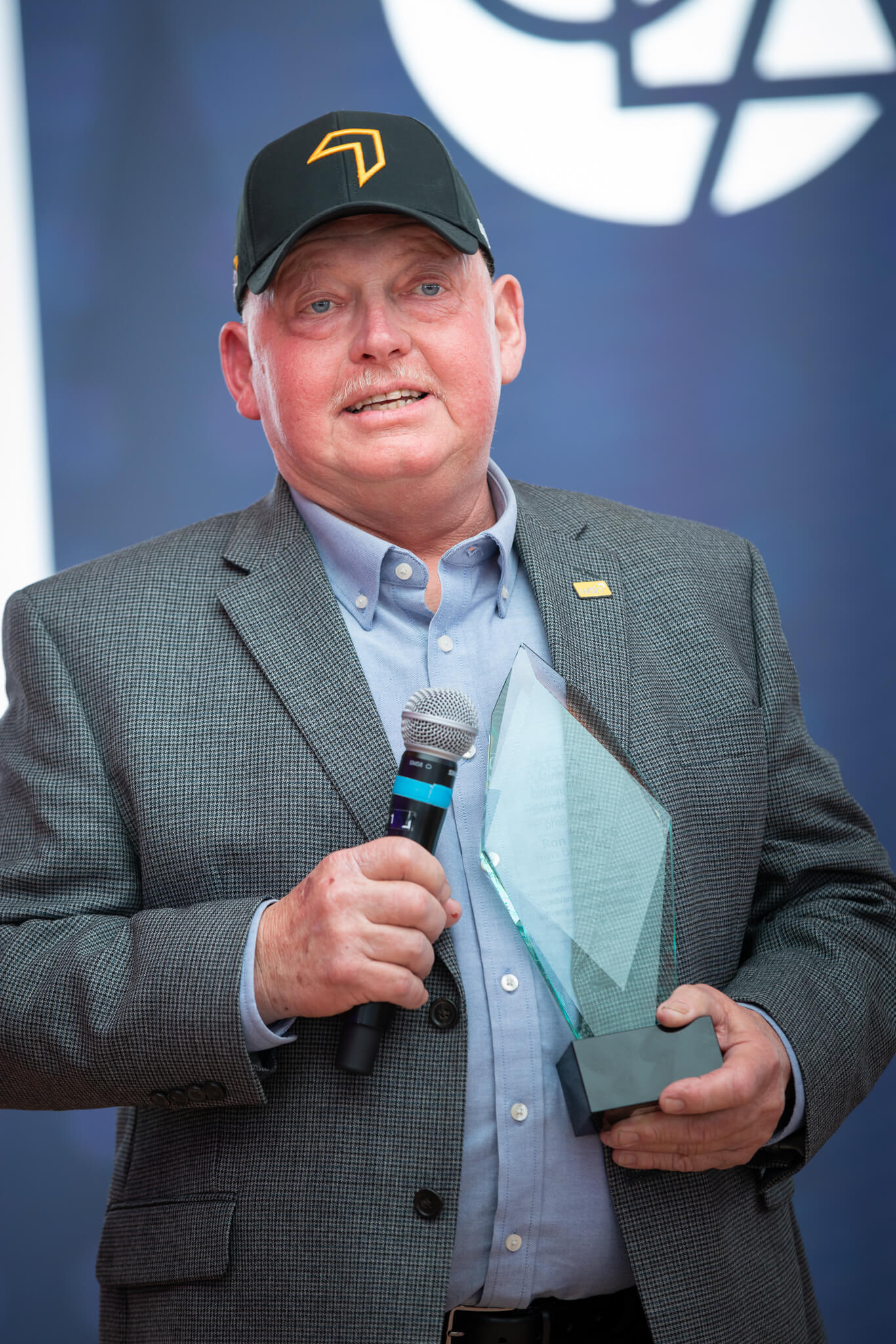 Ron Bray giving his remarks while holding the 2026 Distinguished Service Award