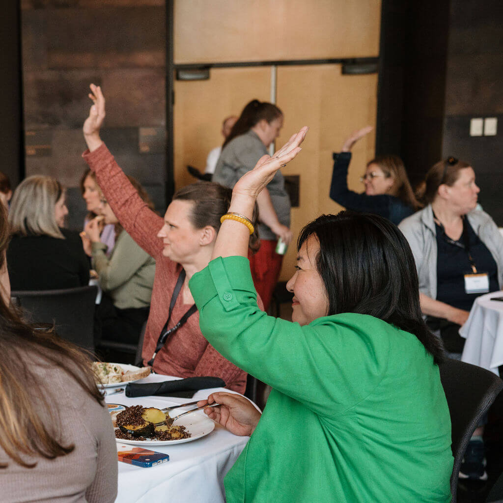 Attendees raise their hands during an interactive lunch session