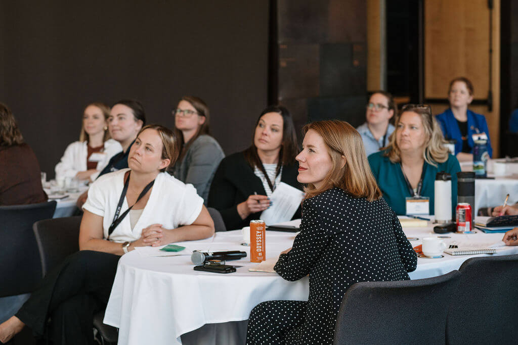 Attendees follow a presentation from their tables