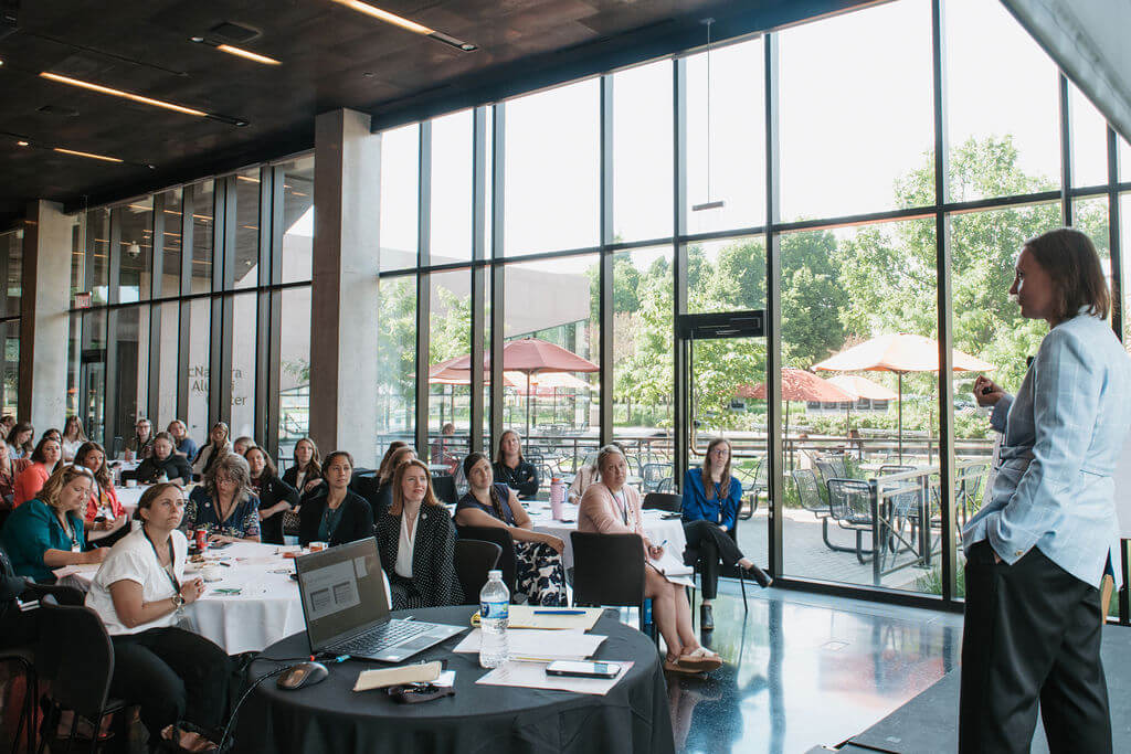 Attendees at round tables listen to a speaker at the Women in Engineering Symposium at the McNamara Alumni Center
