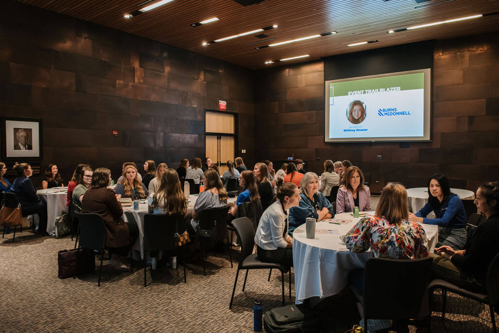 Attendees in conversation at round tables in University Hall