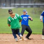 A runner heads for the bag as players in Ayres jerseys look on