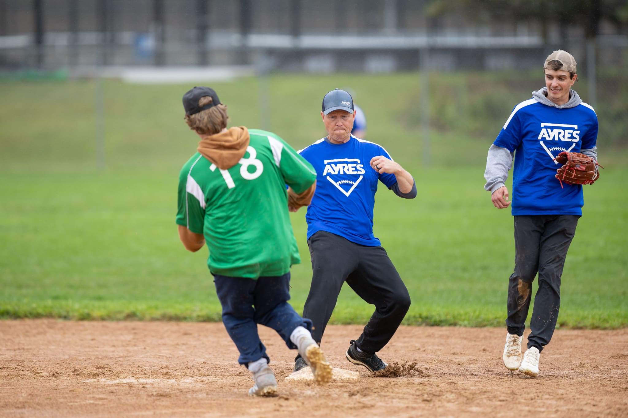 A runner heads for the bag as players in Ayres jerseys look on at Northview Athletic Park