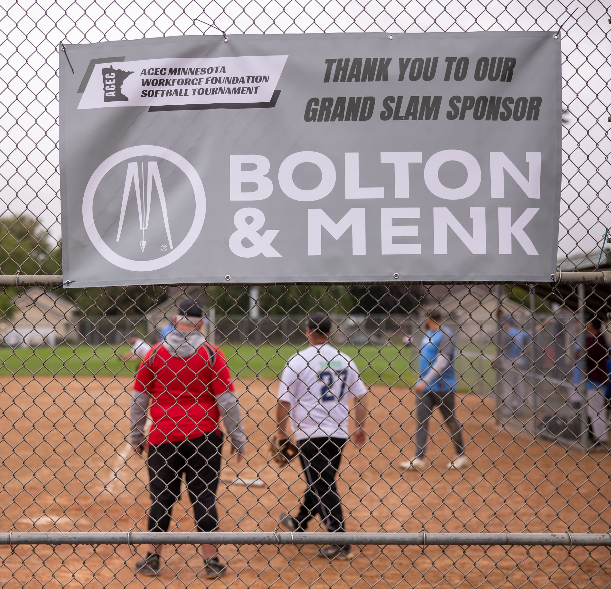 The Bolton & Menk Grand Slam Sponsor banner hangs on the backstop during a game