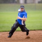 A catcher in blue gear sets up behind the plate