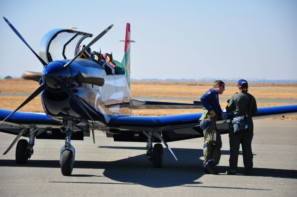 Two people standing by the wing of small airplane