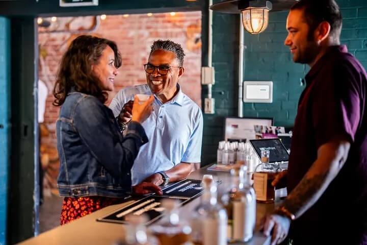 Couple standing at the bar across from the bartender in a distillery