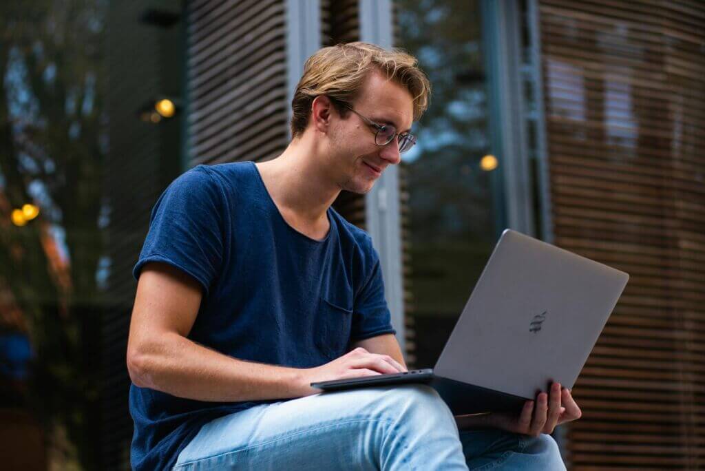 Young student sitting on steps outside working on a laptop