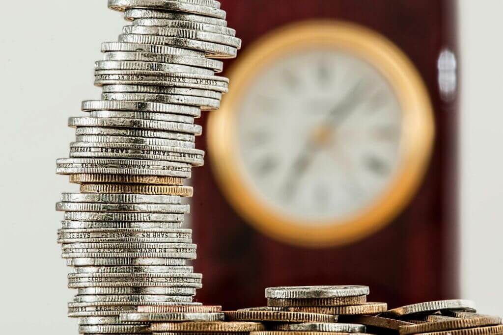 Pile of coins with a clock in the background