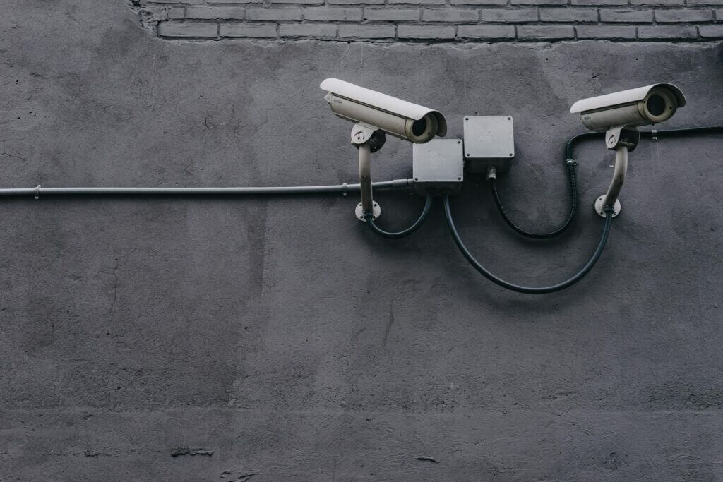 Two security cameras on a grey wall.