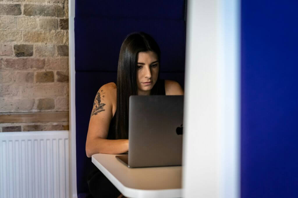 Woman sitting in a booth working on a laptop.