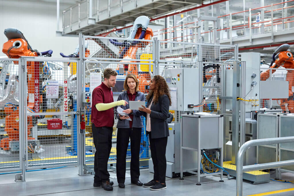 Full length of engineers discussing in car plant Full length of engineers discussing in car plant. Male and female workers are with digital tablet. Professionals are standing in automobile industry.