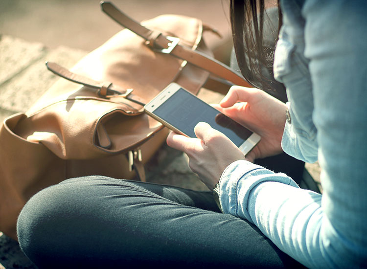 Person sitting outside holding their phone