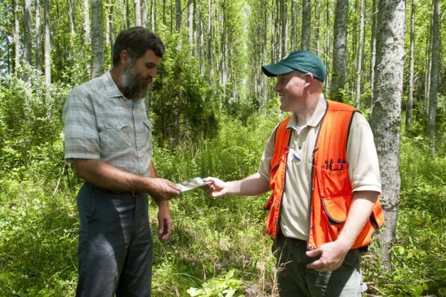 A Michigan Conservation District staff member in a safety vest talking with a local resident outdoors, representing community engagement and technical assistance.