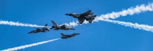 Five U.S. Air Force Thunderbirds performing an aerial maneuver with smoke trails