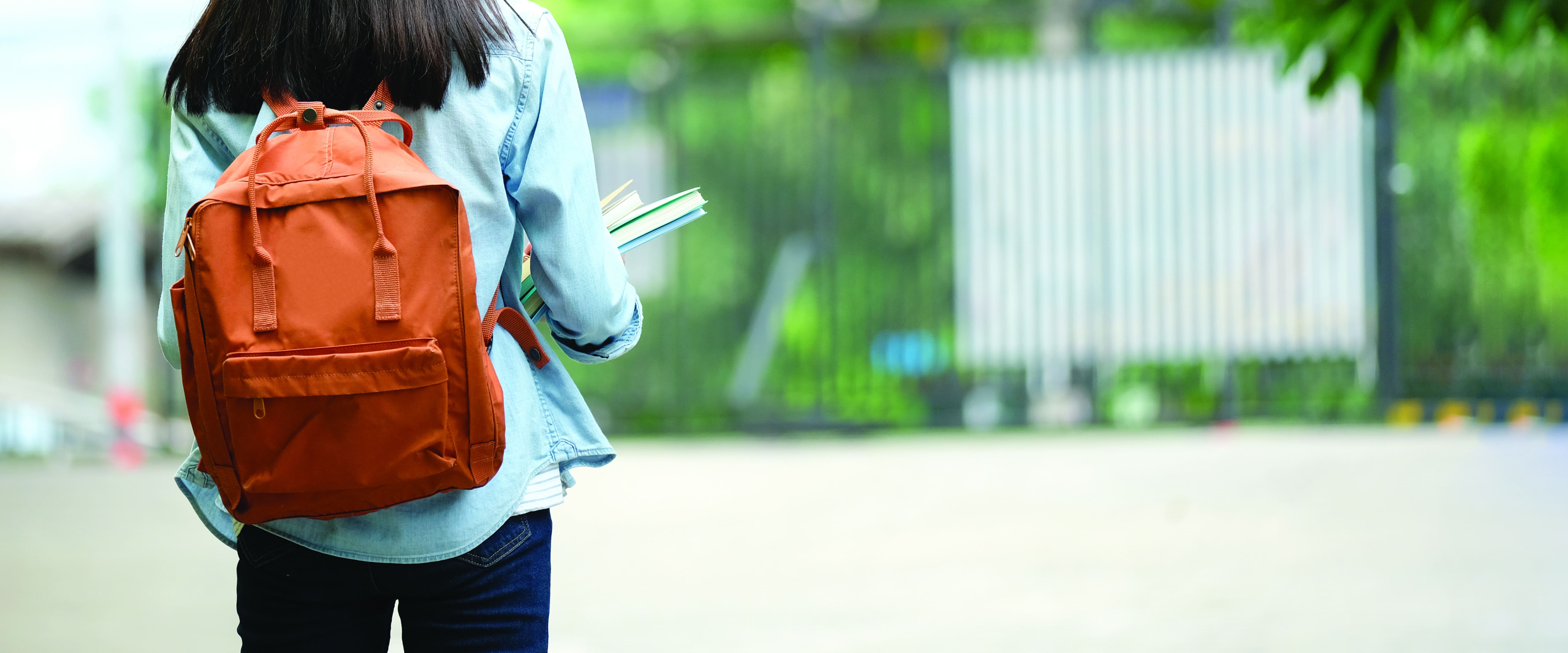 Student carrying books and a backpack representing education opportunities in Bay County, Florida.