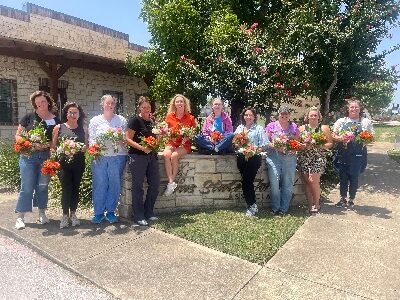 Attendees of the TSFA School of Floral Design pose in front of the TSFA headquarters with floral designs they created